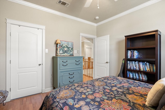 bedroom with light wood-style flooring, a ceiling fan, visible vents, baseboards, and ornamental molding