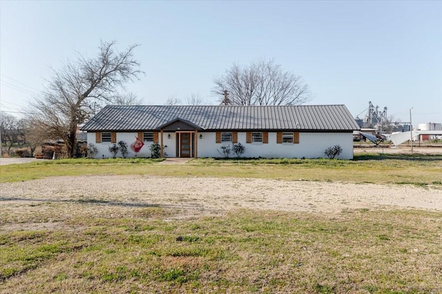 single story home featuring a front lawn, metal roof, and stucco siding