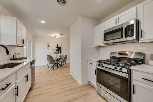 2809 Maple Dr, Garland, TX 75042 - kitchen featuring appliances with stainless steel finishes, a sink, tasteful backsplash, light wood-style flooring, and baseboards
