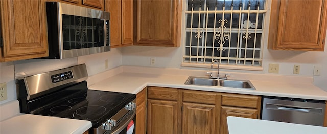 kitchen featuring brown cabinetry, stainless steel appliances, and a sink