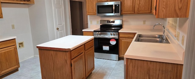 kitchen with light tile patterned floors, brown cabinetry, appliances with stainless steel finishes, and a sink