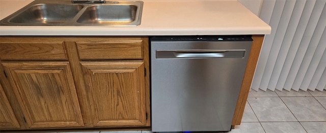 kitchen with dishwasher, light tile patterned flooring, brown cabinets, and a sink