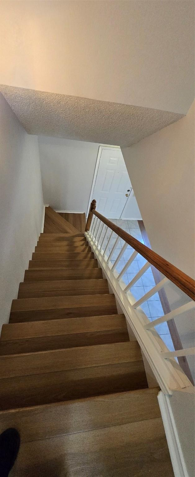 stairway featuring a textured ceiling