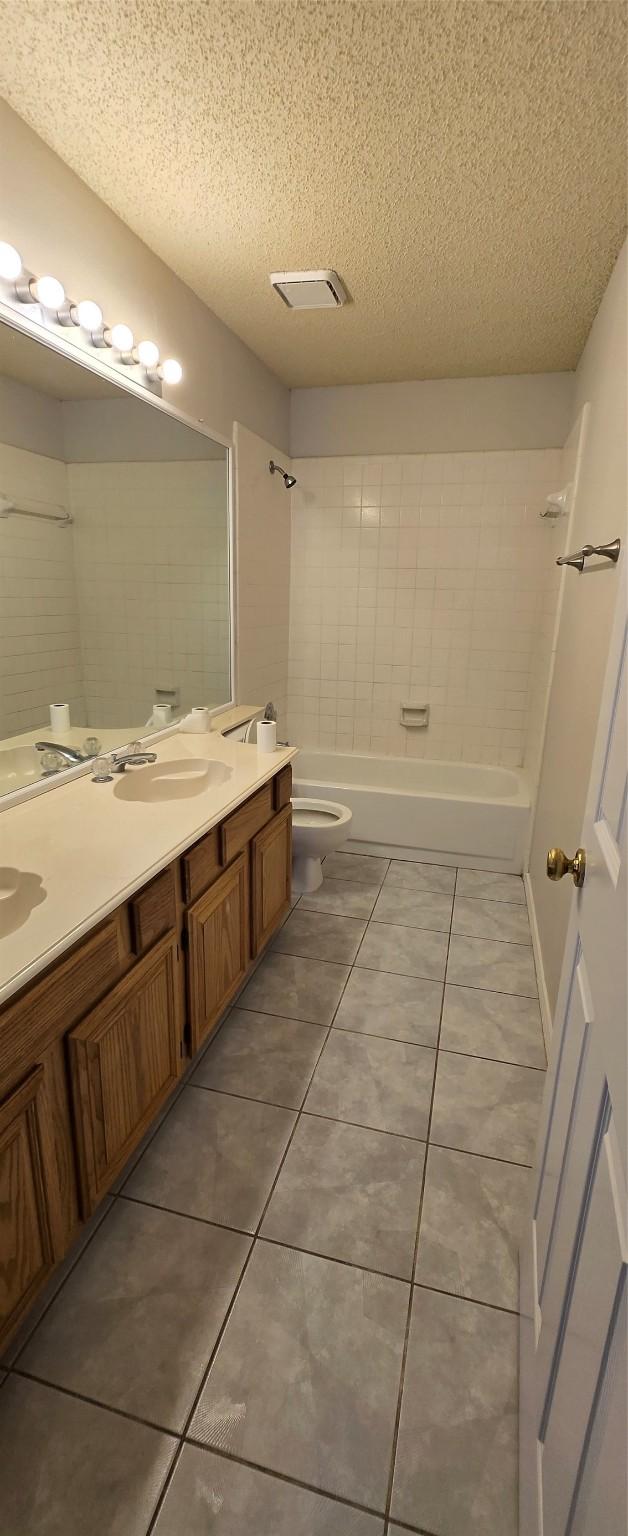 bathroom with double vanity, shower / bathing tub combination, a textured ceiling, and toilet