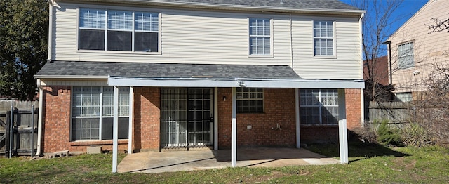 rear view of house with a patio, brick siding, roof with shingles, and fence