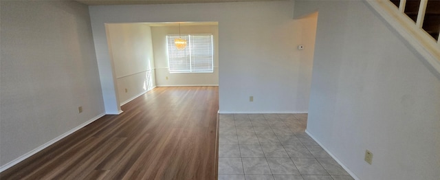 spare room featuring stairway, wood finished floors, and baseboards