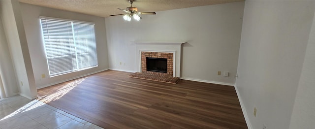 unfurnished living room with a fireplace, a textured ceiling, ceiling fan, and wood finished floors