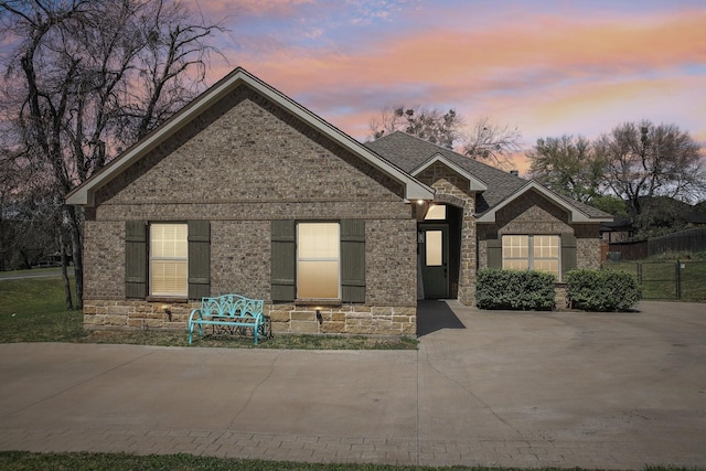 view of front of property featuring brick siding, stone siding, and fence