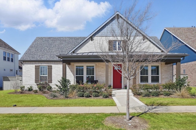 view of front of house with brick siding, a standing seam roof, roof with shingles, and a front lawn