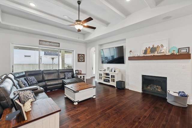 1208 S Pecan Pkwy, Northlake, TX 76247 - living area featuring wood finished floors, a ceiling fan, a brick fireplace, beamed ceiling, and arched walkways