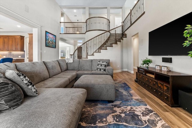 1261 Duke Dr, Prosper, TX 75078 - living room featuring light wood-style floors, stairs, a towering ceiling, and baseboards