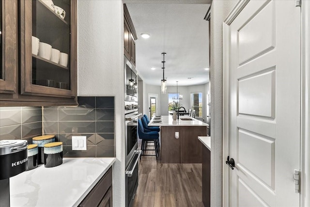 1261 Duke Dr, Prosper, TX 75078 - kitchen with dark wood-style flooring, light countertops, tasteful backsplash, glass insert cabinets, and a sink