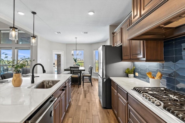 1261 Duke Dr, Prosper, TX 75078 - kitchen featuring light wood-style flooring, appliances with stainless steel finishes, a sink, premium range hood, and backsplash