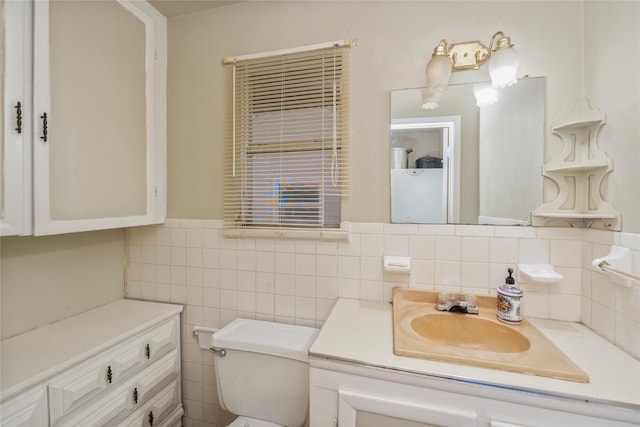bathroom featuring tile walls, wainscoting, vanity, and toilet