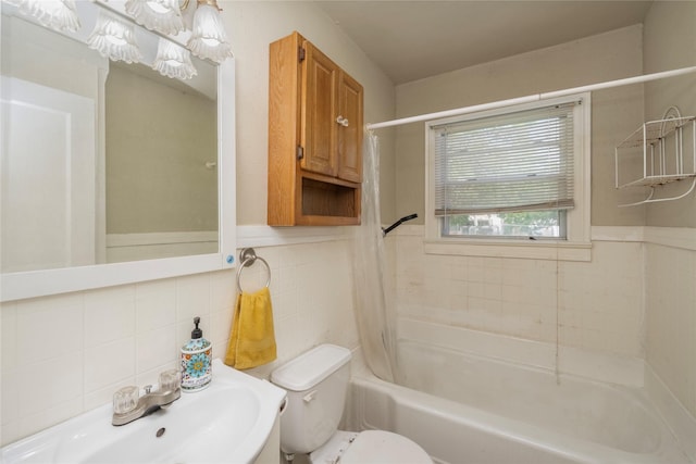 bathroom featuring a sink, wainscoting, tile walls, shower / tub combo, and toilet