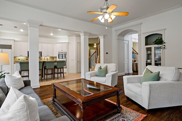 6004 Blossom Ct, Mckinney, TX 75072 - living room featuring ornate columns, ceiling fan, stairway, dark wood-style flooring, and ornamental molding
