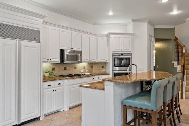 6004 Blossom Ct, Mckinney, TX 75072 - kitchen featuring stainless steel appliances, a breakfast bar, backsplash, dark stone counters, and white cabinetry