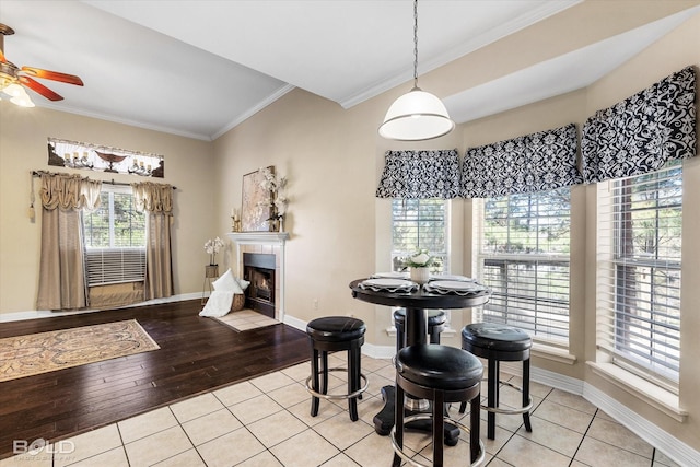 dining space with crown molding, light tile patterned floors, baseboards, ceiling fan, and a fireplace