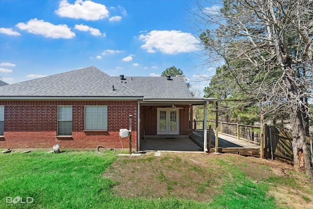 rear view of house with french doors, fence, brick siding, a shingled roof, and a yard