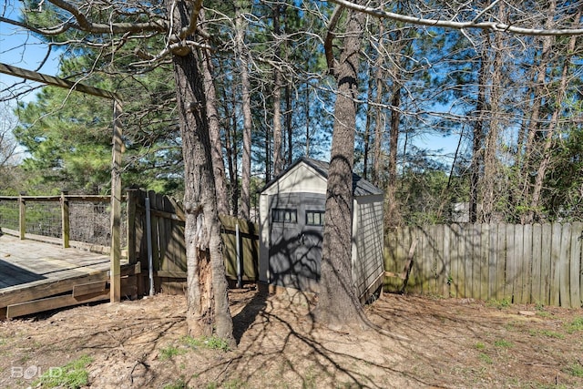 view of yard with an outdoor structure, a fenced backyard, a storage unit, and a wooden deck