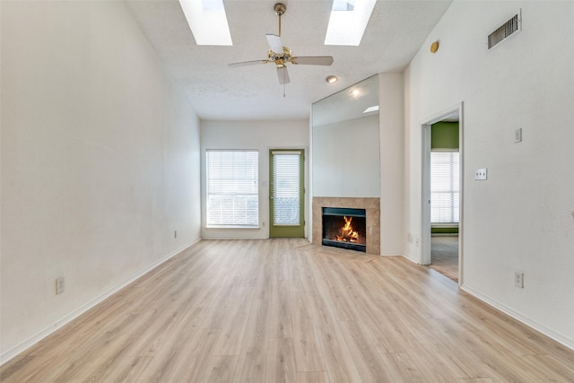 unfurnished living room featuring visible vents, a tile fireplace, a skylight, and plenty of natural light