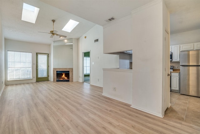 unfurnished living room featuring visible vents, a skylight, and light wood finished floors