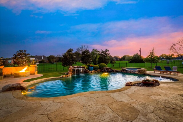 15961 Custer Trl, Frisco, TX 75035 - pool at dusk with an outdoor fire pit, a patio area, a fenced backyard, and a pool with connected hot tub