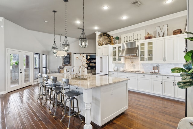 15961 Custer Trl, Frisco, TX 75035 - kitchen featuring wall chimney exhaust hood, freestanding refrigerator, stainless steel gas cooktop, decorative backsplash, and a kitchen island
