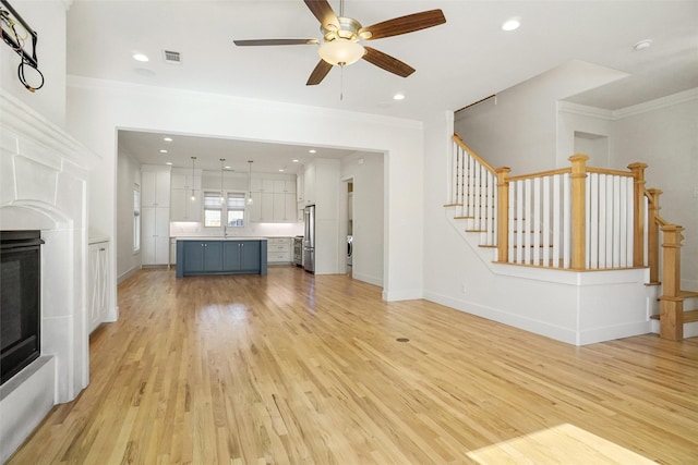 613 E Wall St, Grapevine, TX 76051 - unfurnished living room with visible vents, crown molding, stairway, light wood-style floors, and a glass covered fireplace