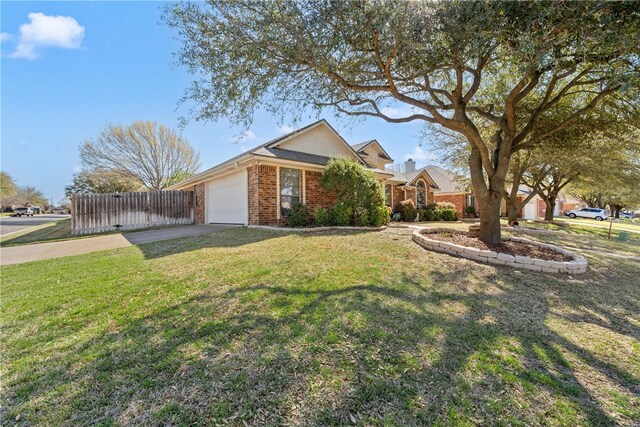 view of front of home with a front yard, concrete driveway, an attached garage, fence, and brick siding