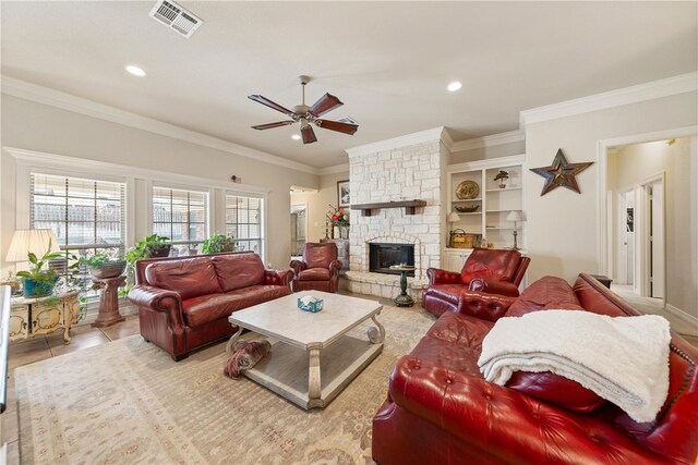 living area featuring visible vents, ornamental molding, tile patterned floors, a ceiling fan, and a stone fireplace