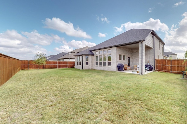back of property featuring a yard, a fenced backyard, brick siding, and a patio area