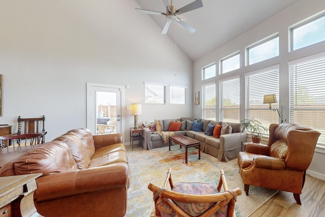 living area with light wood-style floors, high vaulted ceiling, baseboards, and a ceiling fan
