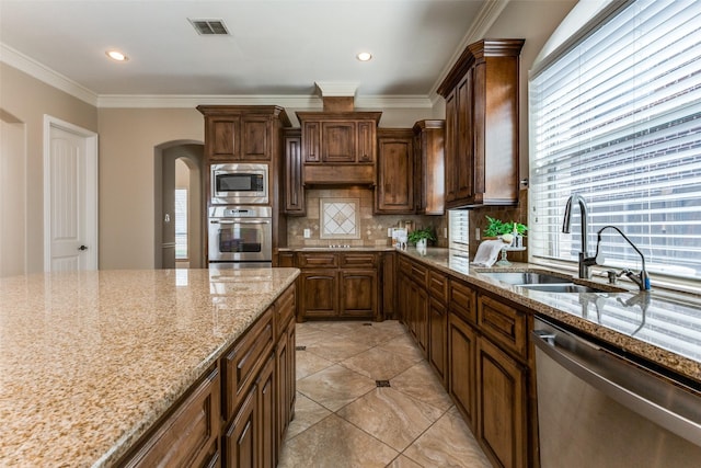 1217 Avondale Dr, Murphy, TX 75094 - kitchen with appliances with stainless steel finishes, a sink, arched walkways, backsplash, and light stone counters