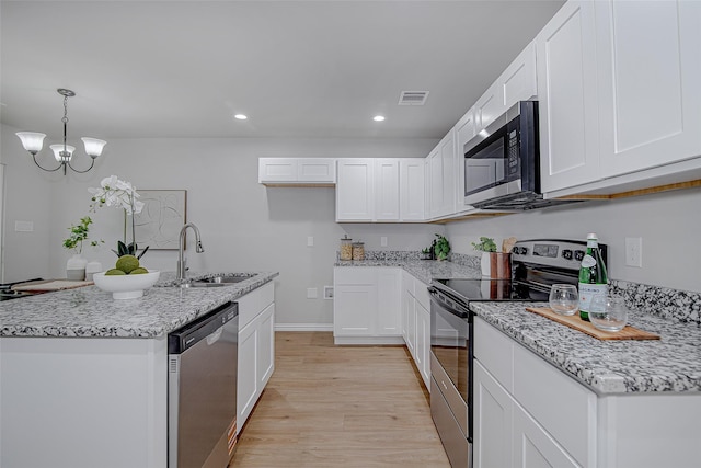 kitchen featuring visible vents, a sink, white cabinets, light wood finished floors, and stainless steel appliances