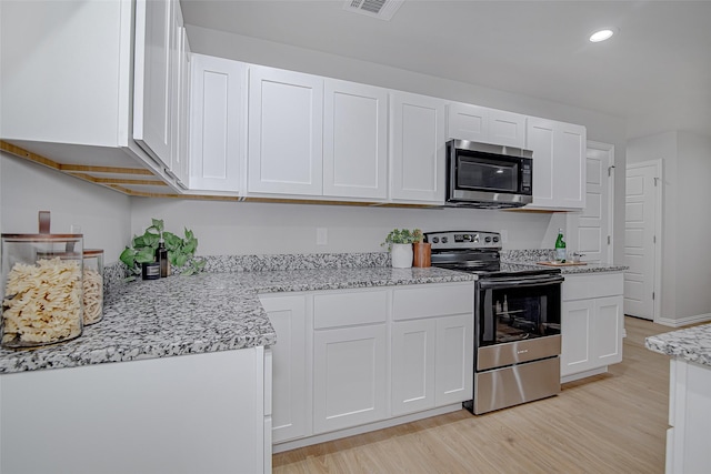 kitchen featuring recessed lighting, light wood finished floors, white cabinets, and stainless steel appliances