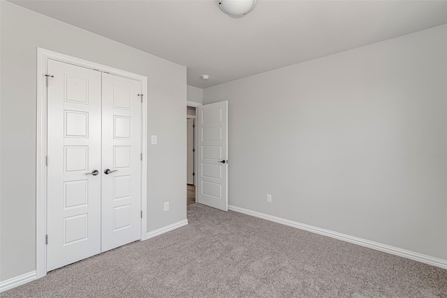 unfurnished bedroom with a closet, carpet, and baseboards