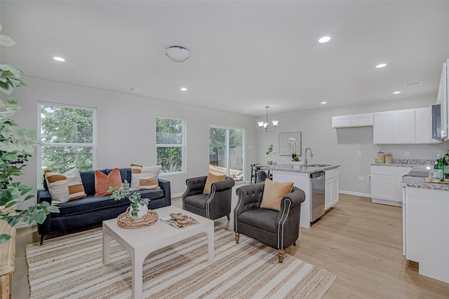 living area featuring recessed lighting, baseboards, light wood finished floors, and a chandelier