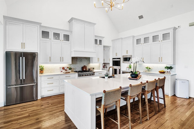 4909 Cheshire Ln, Parker, TX 75002 - kitchen with light countertops, an inviting chandelier, stainless steel appliances, a sink, and a kitchen island with sink
