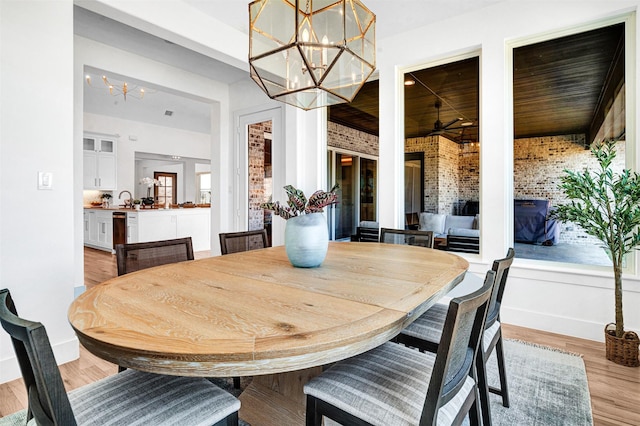 4909 Cheshire Ln, Parker, TX 75002 - dining room featuring light wood-style flooring, a chandelier, baseboards, brick wall, and wooden ceiling