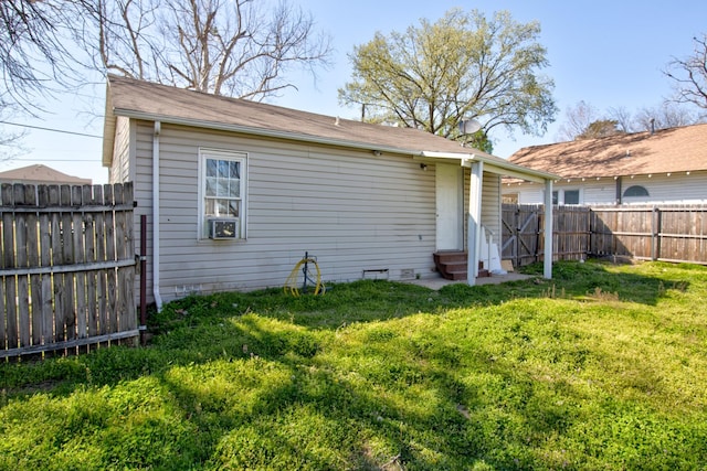 rear view of property featuring a lawn, a fenced backyard, and entry steps