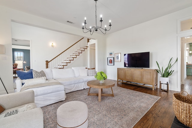 living area with an inviting chandelier, dark wood-style flooring, stairs, and visible vents