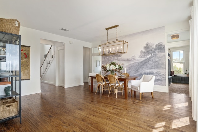 dining area featuring an inviting chandelier, wood finished floors, visible vents, baseboards, and stairs