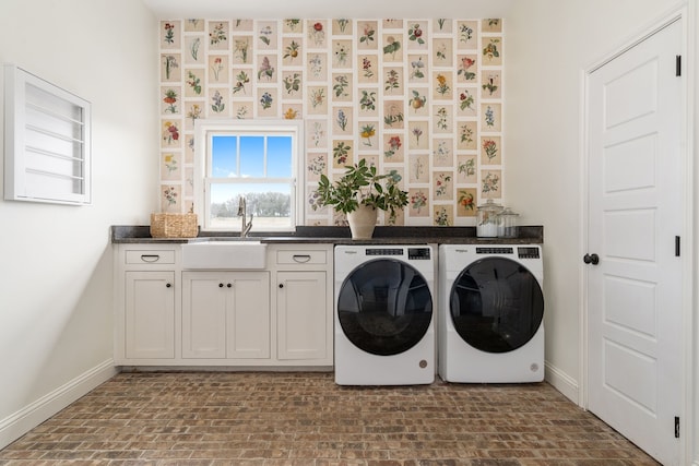 laundry room with brick patterned floor, a sink, washing machine and dryer, baseboards, and cabinet space