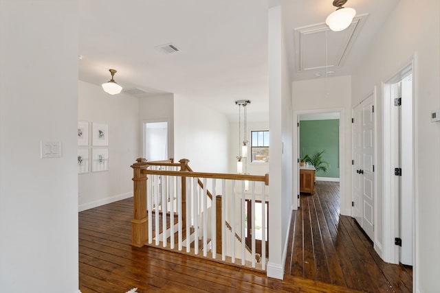 hallway with an upstairs landing, attic access, hardwood / wood-style flooring, baseboards, and visible vents