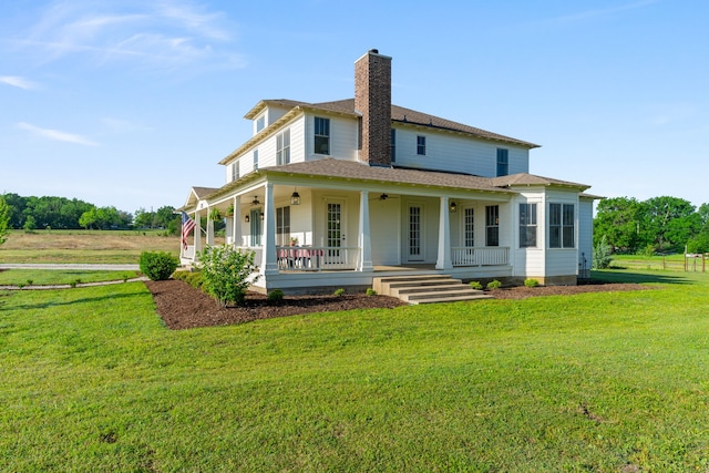 back of house with a chimney, a lawn, ceiling fan, and covered porch