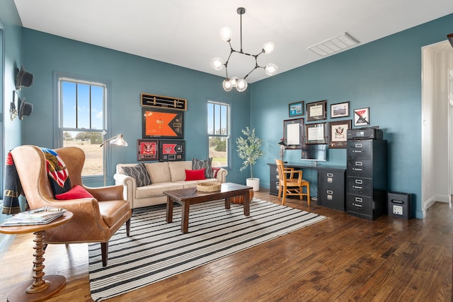 living room featuring visible vents, baseboards, wood finished floors, and an inviting chandelier