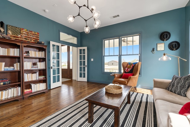 living room featuring french doors, visible vents, baseboards, a notable chandelier, and wood finished floors