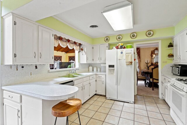 kitchen featuring light tile patterned floors, light countertops, white cabinets, and white appliances