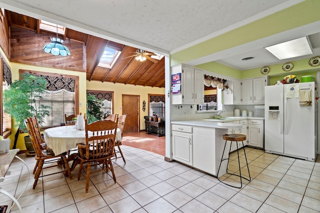 kitchen featuring light countertops, visible vents, white cabinets, white fridge with ice dispenser, and light tile patterned floors